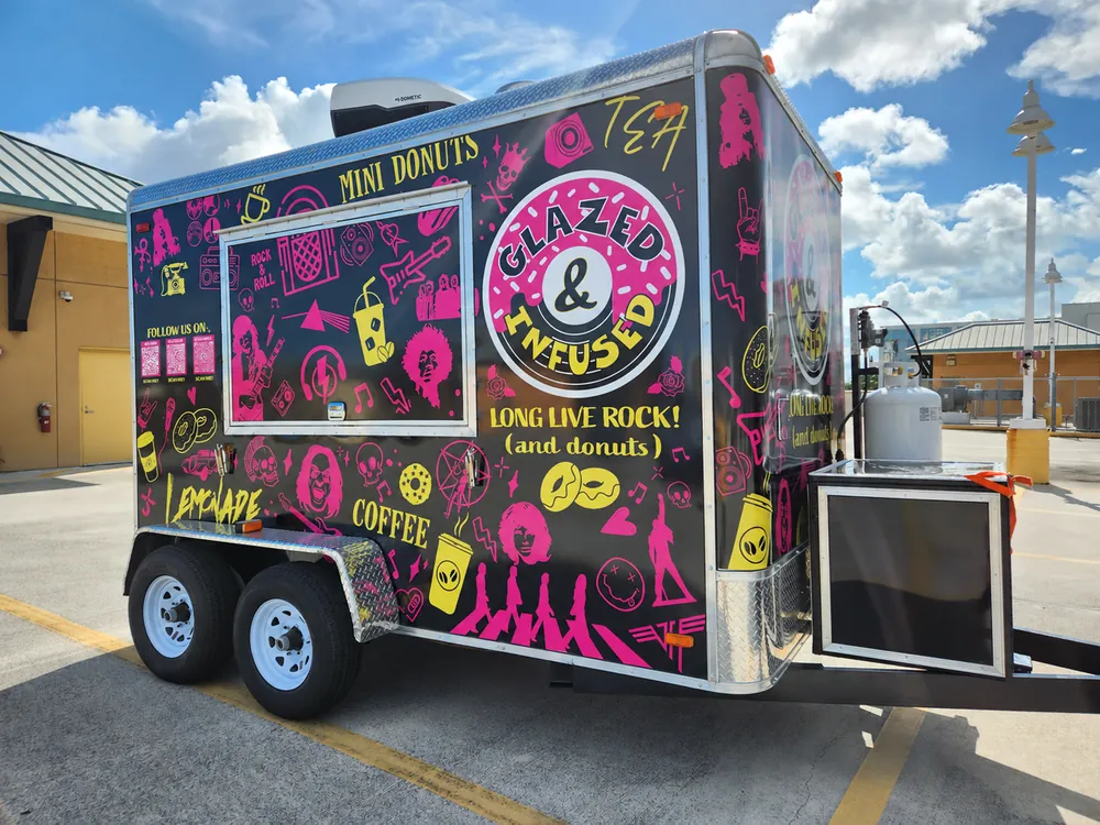 Glazed and Infused trailer in a sunny parking lot, showing its rock artwork and logo
